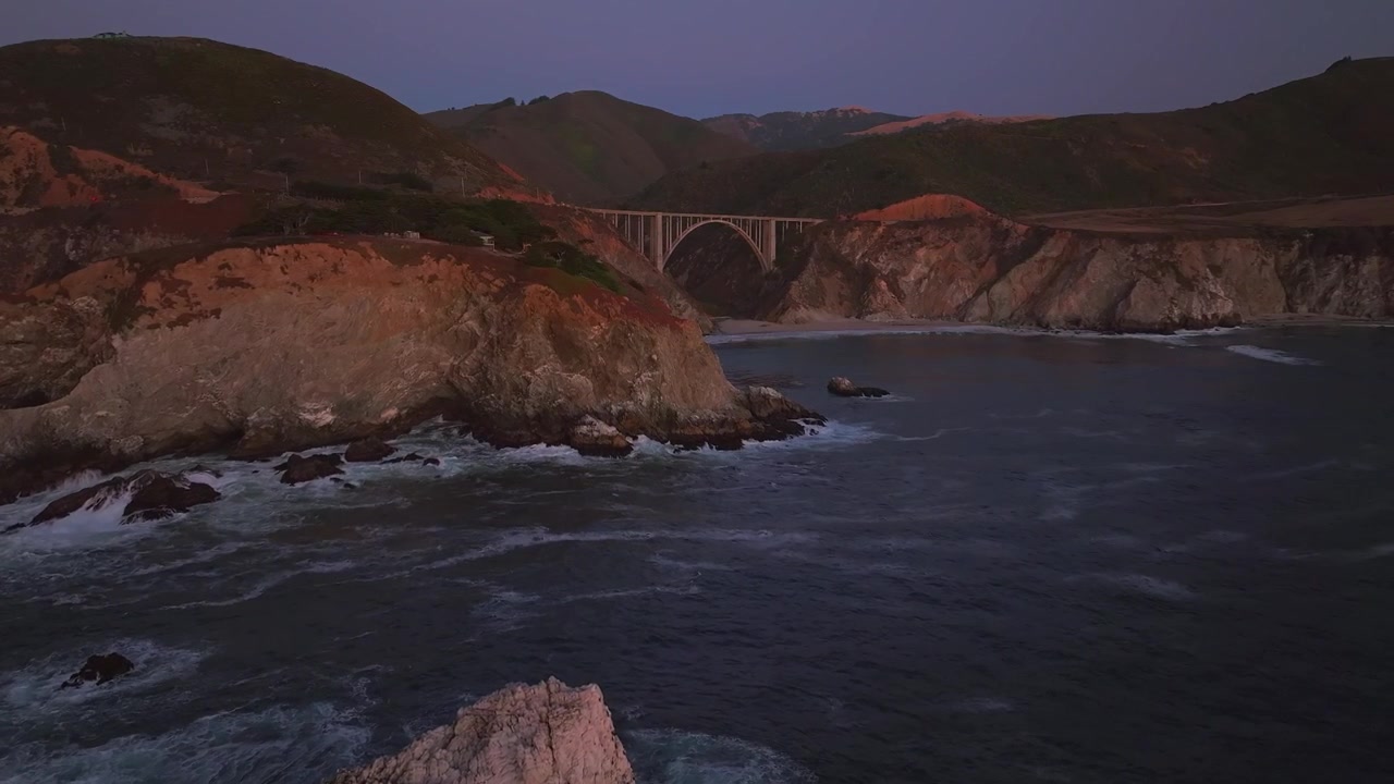 Costa frastagliata di Big Sur, California, con il Ponte Bixby, Big Creek, Pfeiffer Canyon e le Montagne di Santa Lucia. Ripresa aerea con drone di un tramonto mozzafiato sull'Oceano Pacifico, lungo la Strada Costiera ventosa, con onde che si infrangono, ripresa statica.