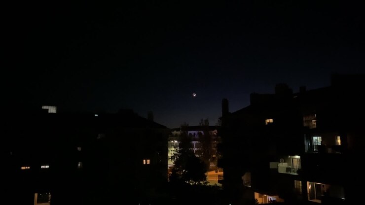 Tramonto in città con la luna sullo sfondo.
