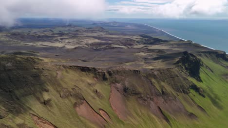 aerial panoramic view of icelandic landscape with mountains near vik city, iceland. aerial panning shot. green mountains and hills with blue sea water. wide shot