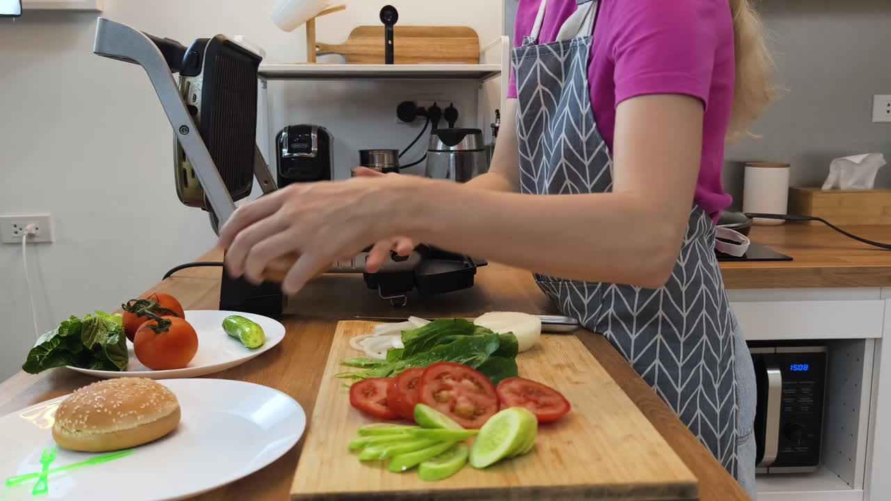 una mujer haciendo una hamburguesa.