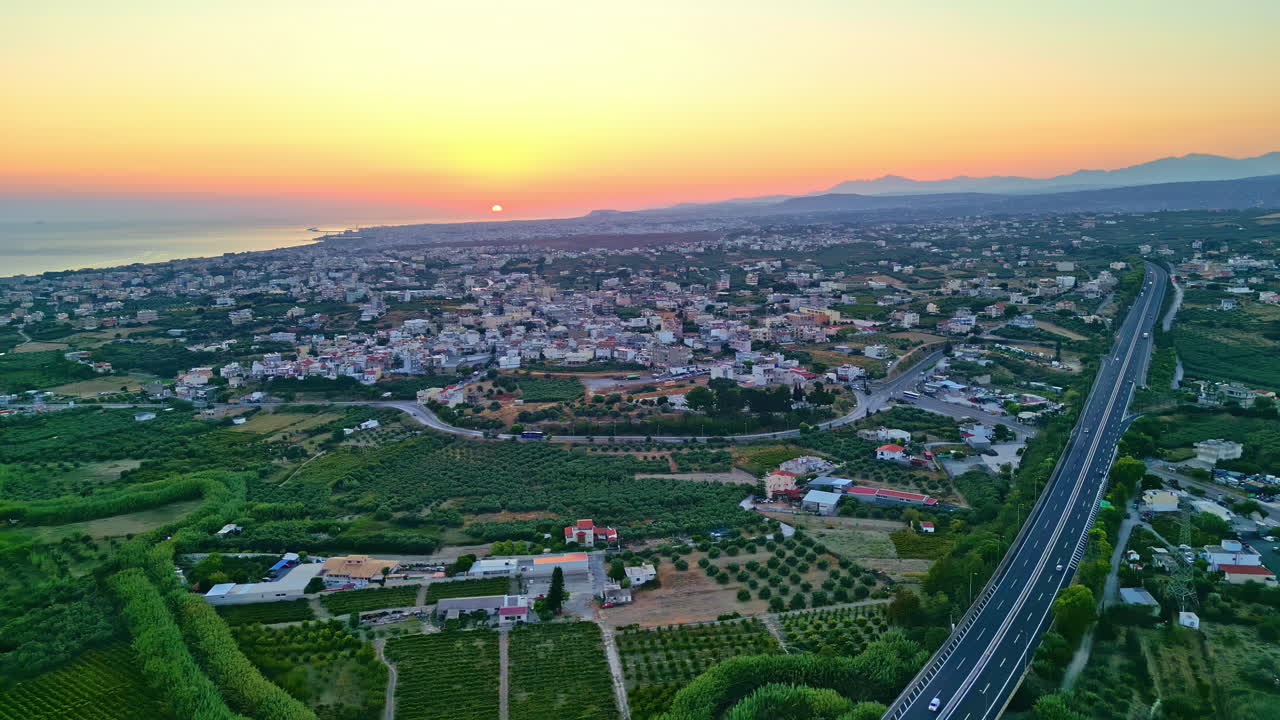 High angle drone shot of a greek cityscape during sunset at horizon in Knossos,Greece.. Expressways in front.
