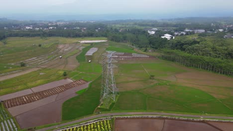 Tiro-De-Ojo-De-Pájaro-Con-Drones-De-Una-Torre-De-Electricidad-De-Alto-Voltaje-En-Medio-De-Un-Campo-De-Arroz---Asia