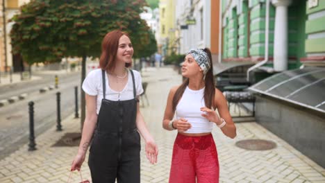 two young women walking and talking on a city street