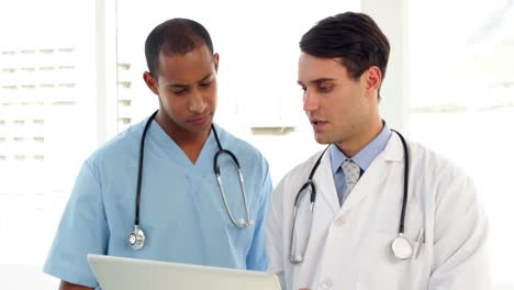 Medical-workers-looking-over-file-on-clipboard