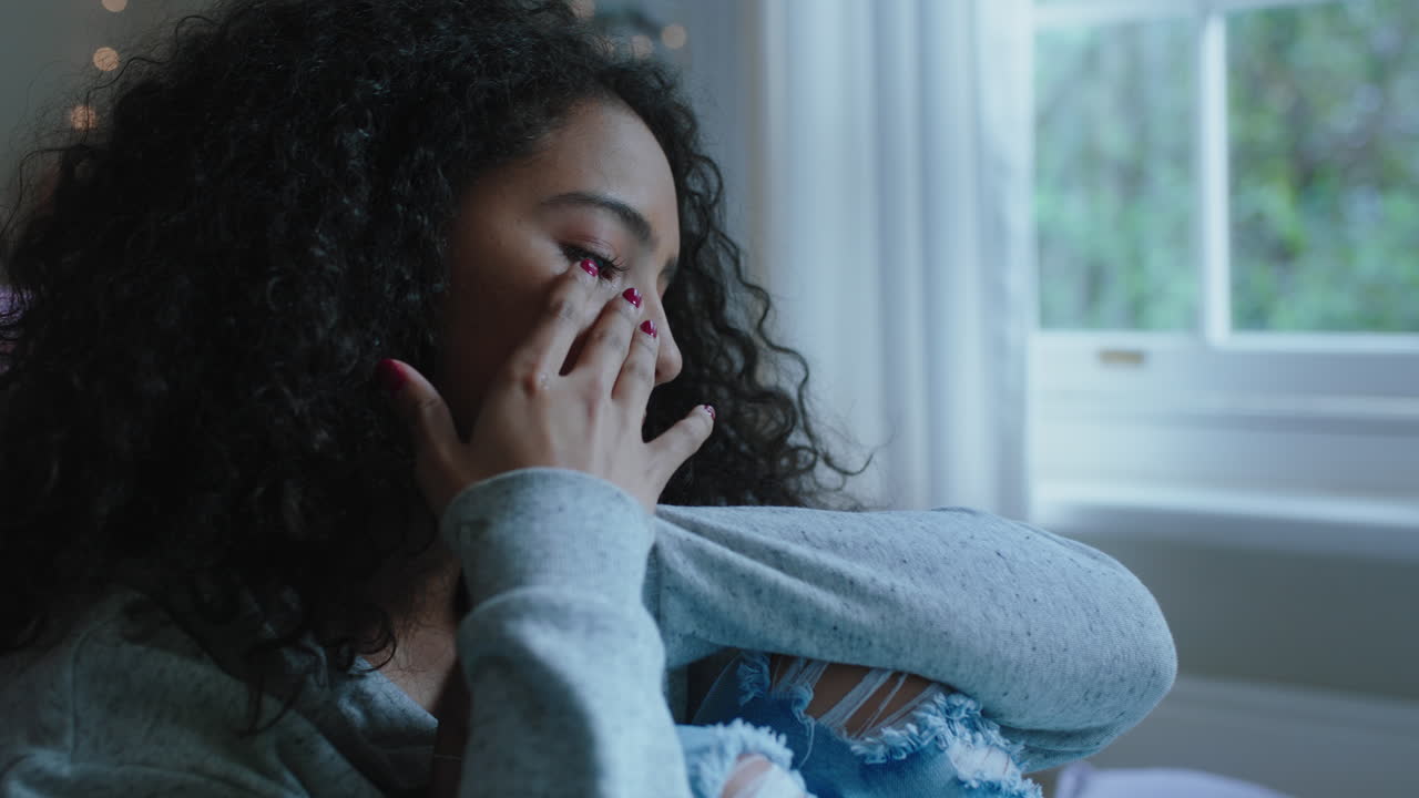 sad teenage girl crying at home feeling alone depressed teen thinking of emotional break up sitting in bedroom