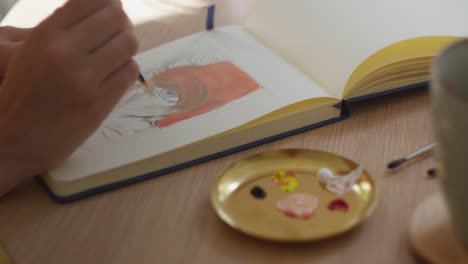 her paintbrush adds colour to her painting on the page