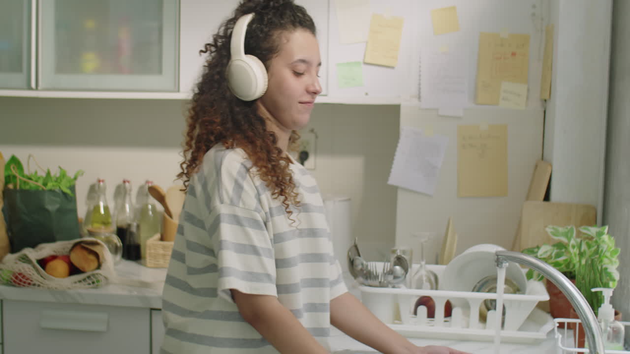Girl in Headphones Doing Dishes at Home
