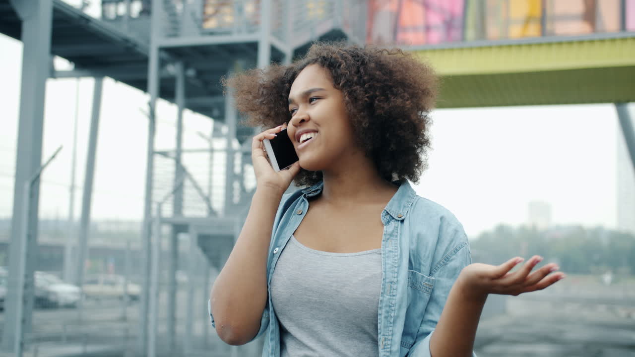 Giovane donna che parla allo smartphone in ambiente urbano