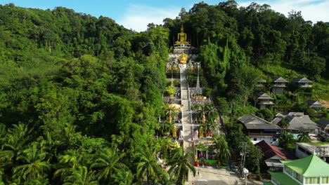 iconic buddha mountain temple in the middle of a deep tropical forest, palm trees, krabi, thailand, drone shot