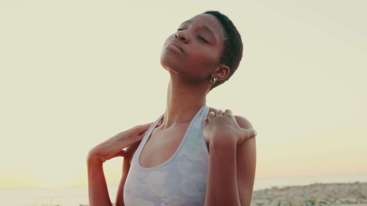 Giovane donna afroamericana che fa stretching al collo e alle spalle all'aperto