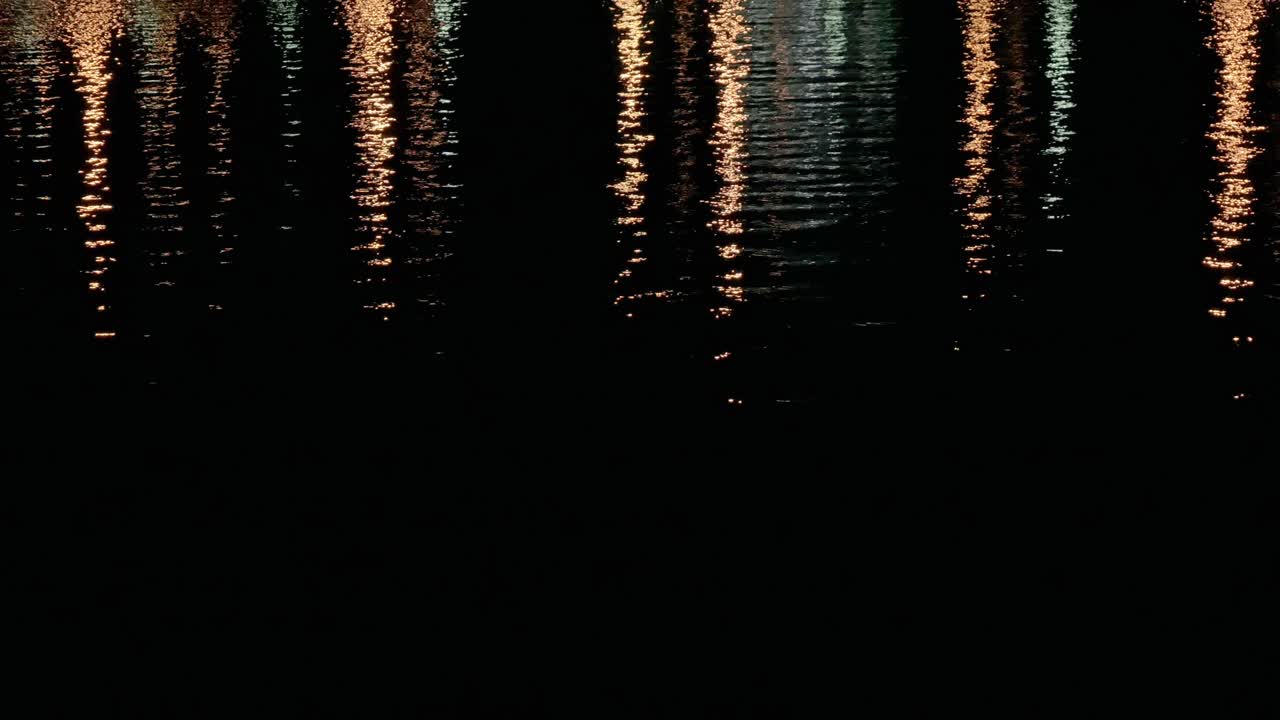 superficie de agua nocturna de la bahía del crepúsculo con luz de la ciudad