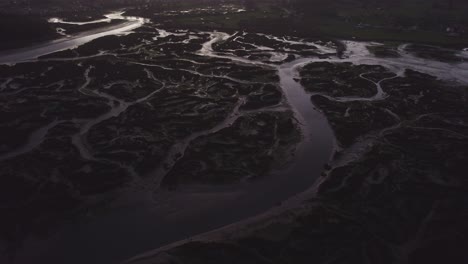 river estuary silted mudflats fluvial tidal water patterns at dusk aerial