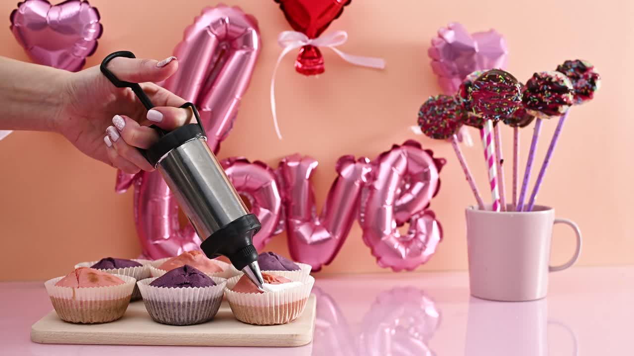 크림으로 귀여운 특별한 분홍색과 보라색 컵 케이크를 장식합니다. 발렌타인 데이를 위해 사탕과 디저트를 만드는 것.