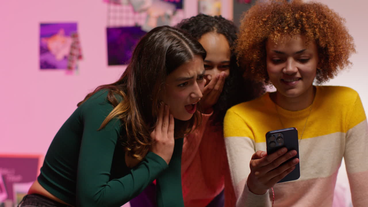 amigos mirando un teléfono en un dormitorio