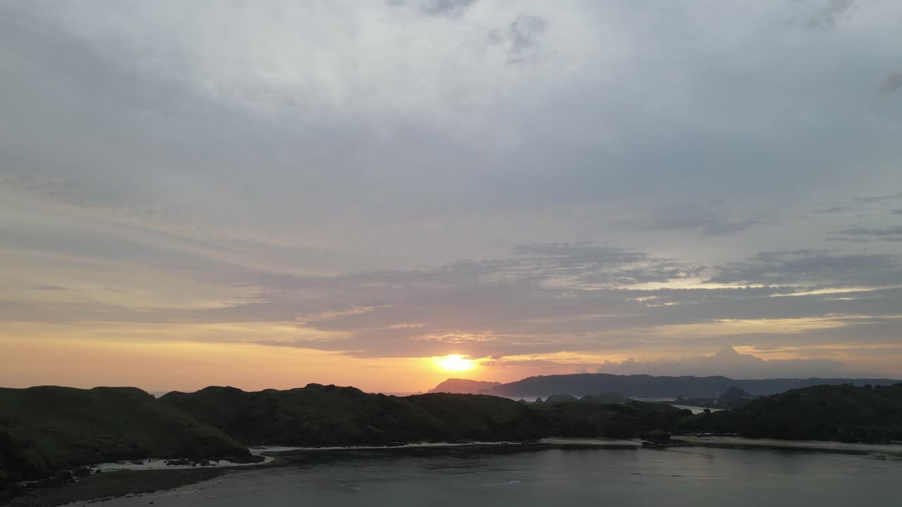 黄金色の光が輝く、雲の多い穏やかな海岸の夕焼け