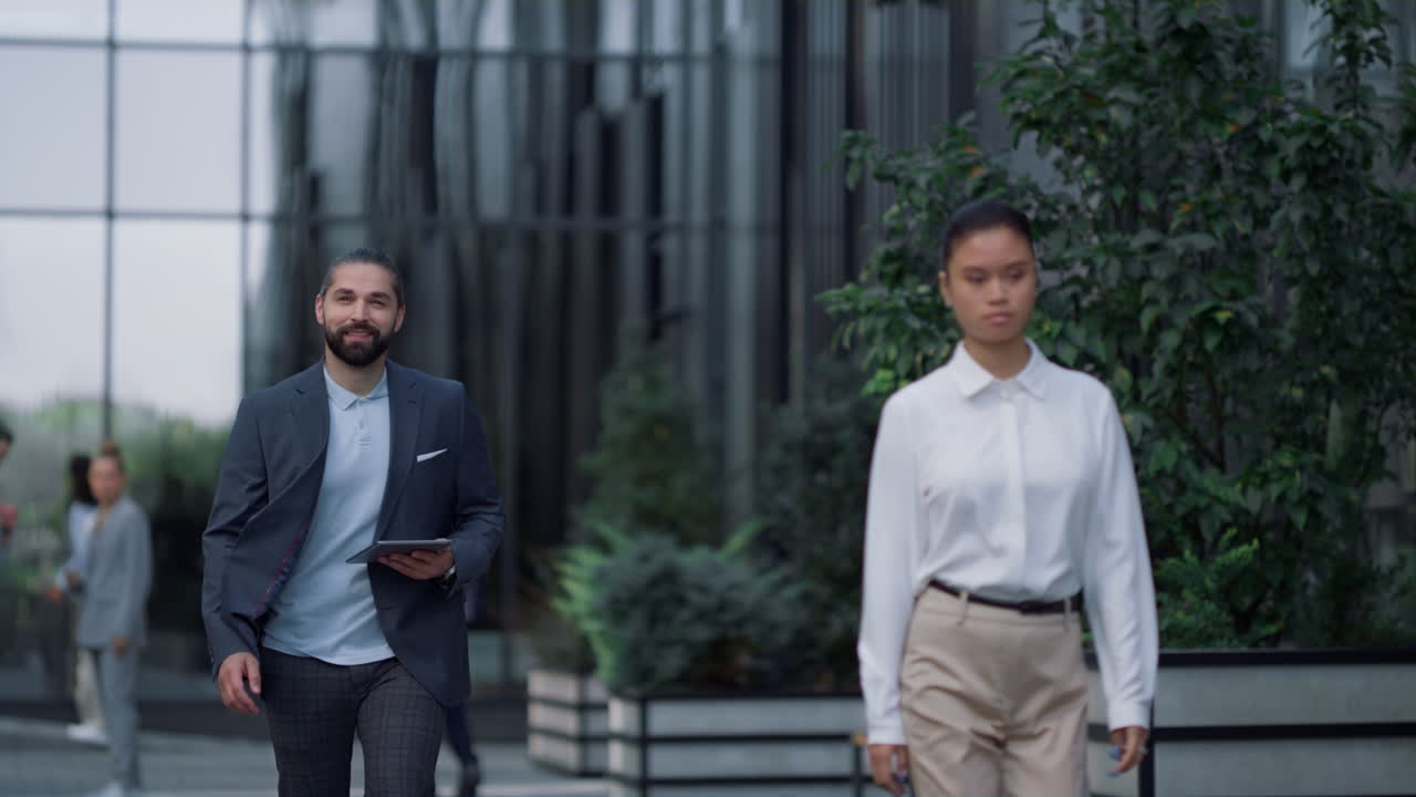 Smiling businessman walking with tablet computer at downtown business center.