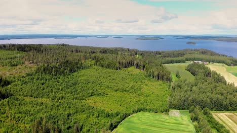 aerial view of finnish countryside and forest with a lake and islands in the background on a summer day