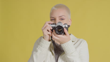 modelo caucásica femenina posando con slr vintage contra fondo amarillo 05