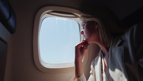 Business-Woman-With-Glasses-Flying-In-An-Avión-Looking-Out-The-Window