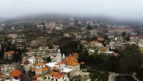 Toma-Aérea-Cinematográfica-De-Un-Pueblo-Libanés-Y-árboles-En-La-Niebla-De-La-Mañana.