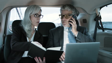 businessman talking on phone and his assistant showing notes to him