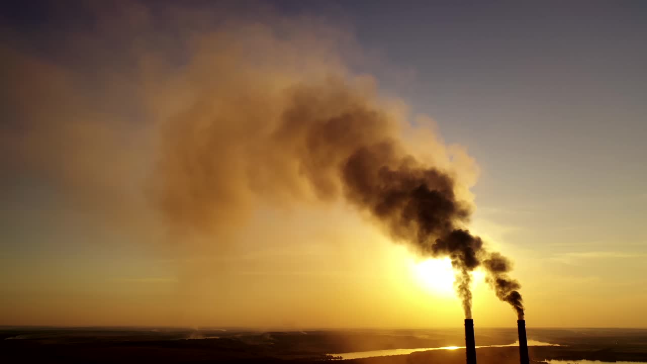 Air pollution at sunset. Industrial pipes with dirty smoke pollute the atmosphere. Two big pipes with toxic smoke in the evening.