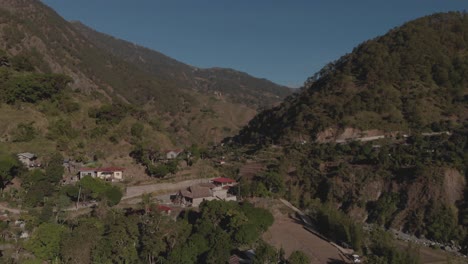 remote village town in mountainous tropical region kabayan benguet philippines aerial fast approaching wide angle approaching house on edge of valley blue sky sunny day
