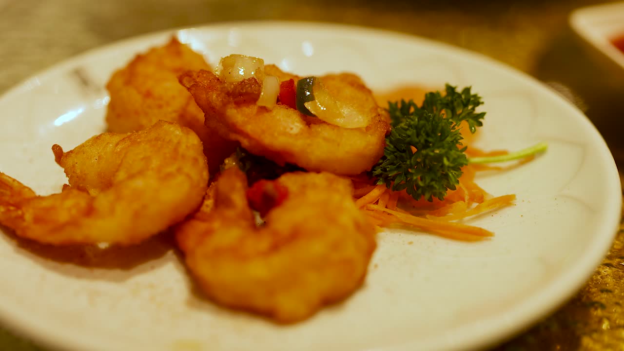Golden deep-fried shrimp served with garnish on a white plate, captured in warm lighting at a Gold Coast restaurant