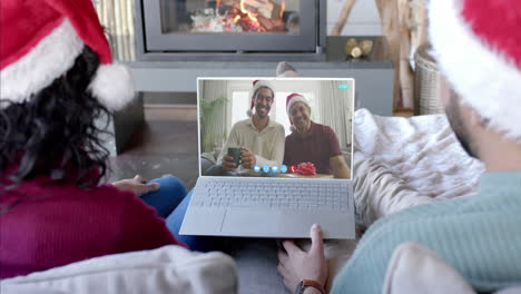 happy diverse couple and male relatives having christmas laptop video call, slow motion