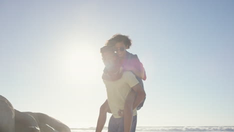 Hombre-Atractivo-Dando-Novia-A-Cuestas-Pareja-De-Raza-Mixta-Disfrutando-De-La-Naturaleza-En-La-Playa