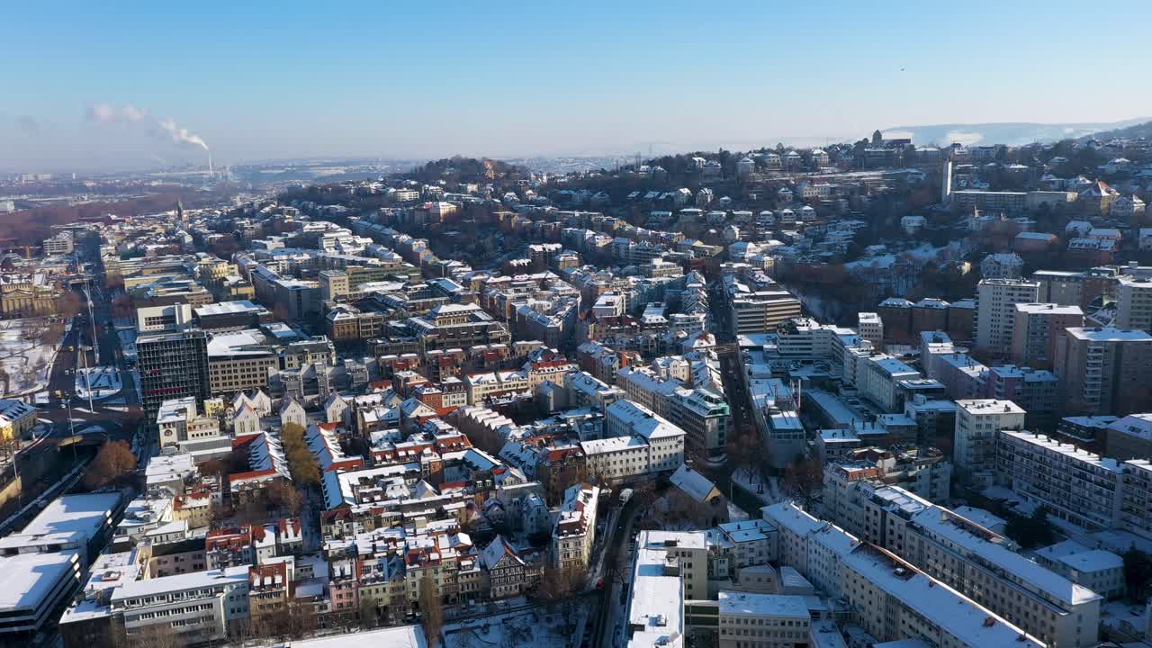 panorámica aérea e inclinación a través del hermoso horizonte de la ciudad con techos de tejas rojas, calles y montañas cubiertas de nieve durante el invierno en stuttgart, alemania