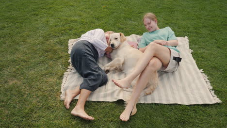 grandparents and granddaughter relaxing with a dog on a picnic blanket