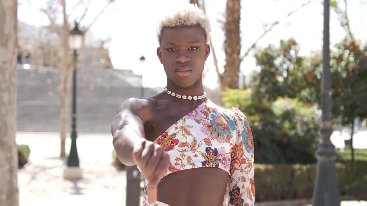 Transgender person looking angry and upset while standing outdoors with arms crossed.