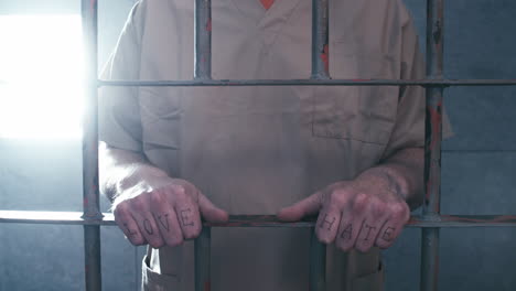 plano medio de un prisionero con "amor" y "odio" tatuado en los nudillos mientras la cámara avanza, luego se aleja