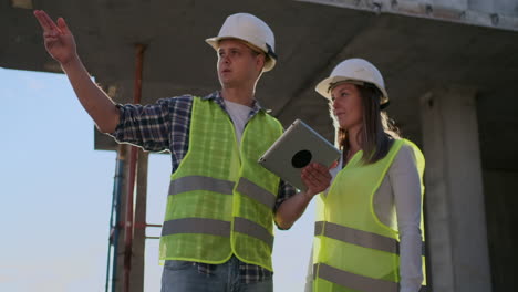 ingenieros profesionales con chalecos de seguridad y cascos que trabajan con tabletas digitales y planos