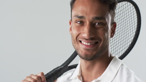 Young-biracial-man-poses-with-a-tennis-racket