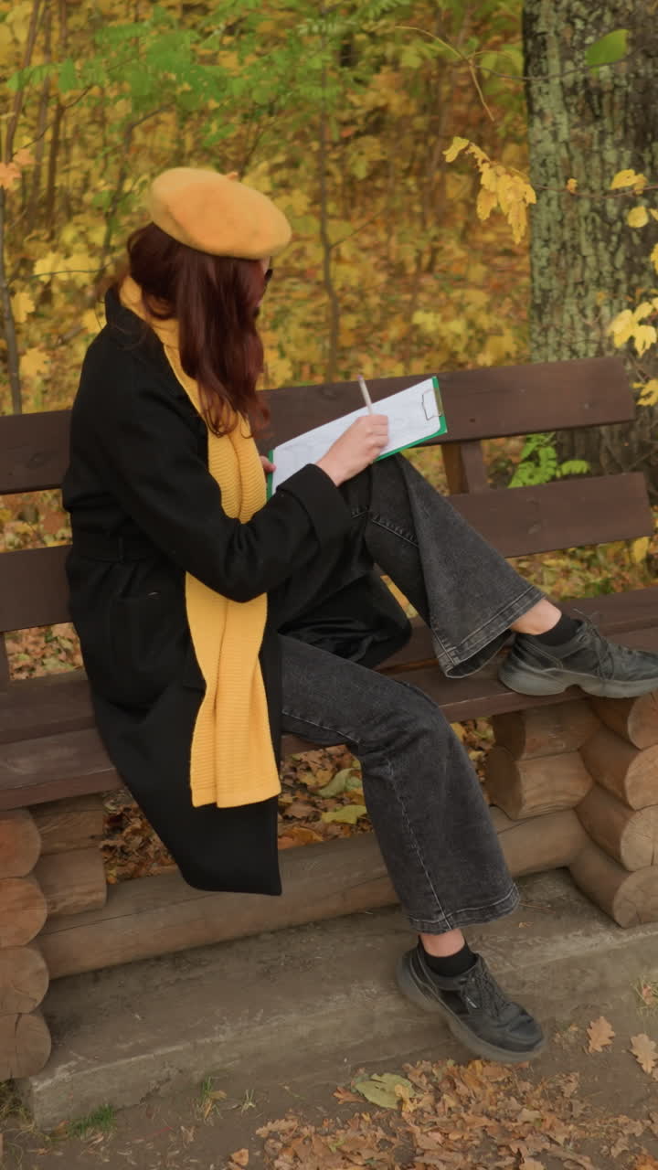 vista aérea de la mente creativa dibujando sentada al aire libre en un banco de madera en soledad, rodeada de coloridas hojas de otoño, centrándose en la expresión artística en un entorno forestal tranquilo