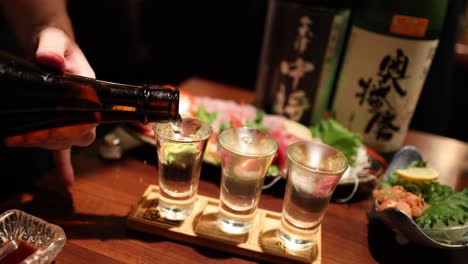 sequential sake pouring into glasses at a bar