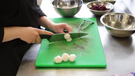 cocinero de la cocina cortando verduras en una tabla de corte verde