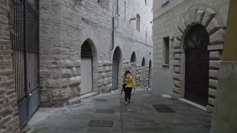 A-lone-female-tourist-walks-the-quiet-back-streets-of-the-old-city-of-Perugia,-Province-of-Perugia,-Italy