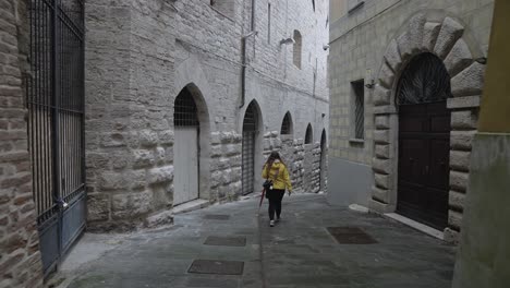 una turista solitaria camina por las tranquilas calles de la ciudad antigua de perugia, provincia de perugia, italia