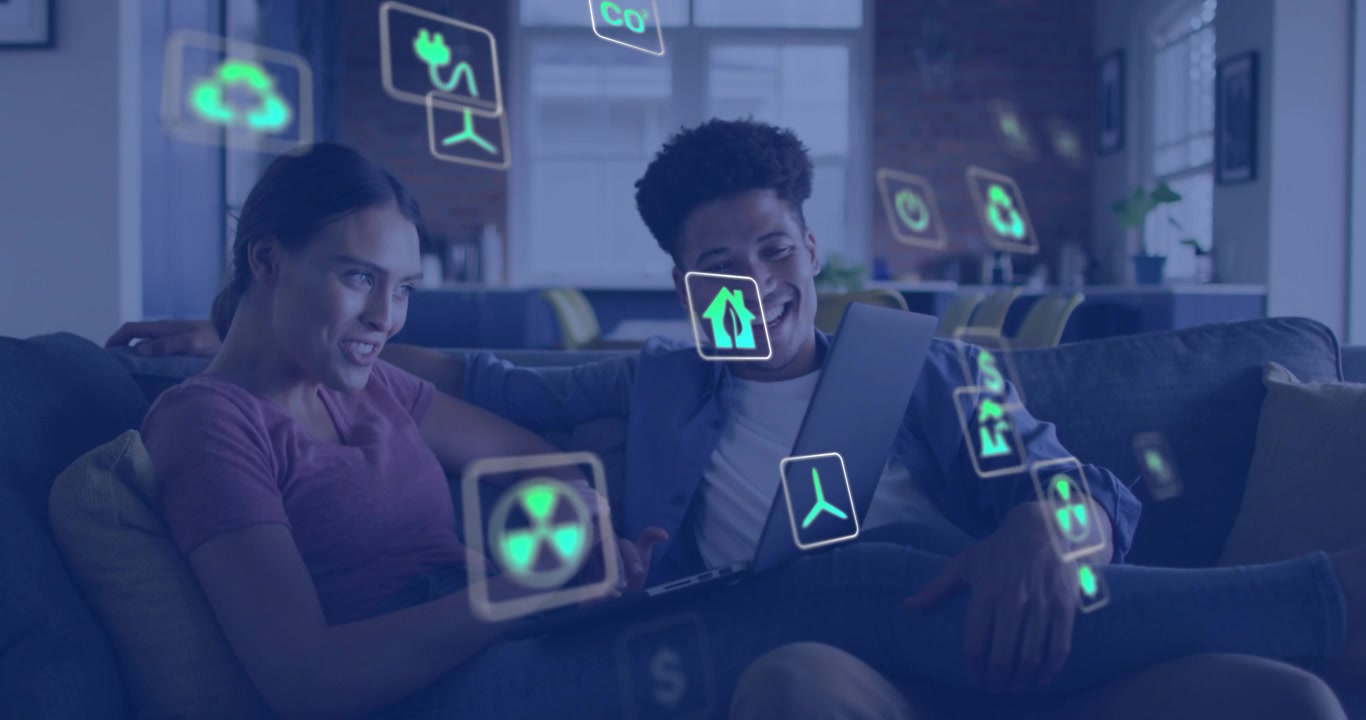 Pointing woman typing on laptop on sofa as drifting teal icons causing action, man leaning smiling