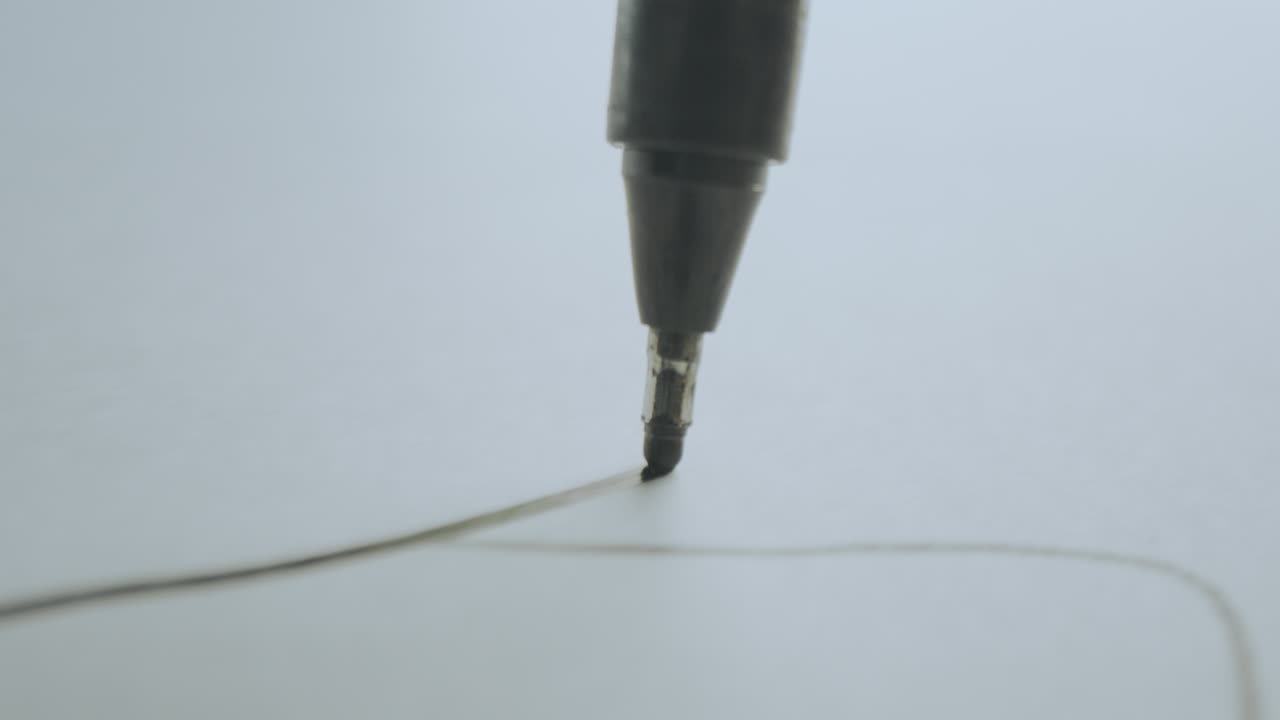 Close-up of a pen drawing a line on paper