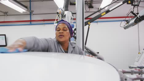 mecánica de automóviles afroamericana limpiando el techo de un coche con un trapo