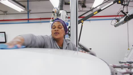 african american female car mechanic cleaning the roof of a car with a rag