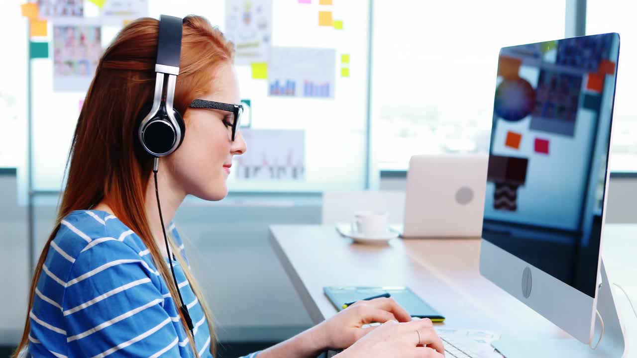 Female graphic designer working while listening music at desk