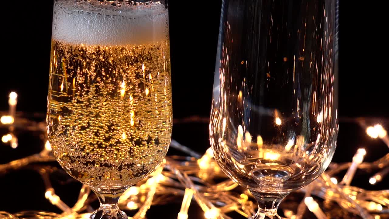 Calici da champagne e una rosa sullo sfondo di ghirlande luminose