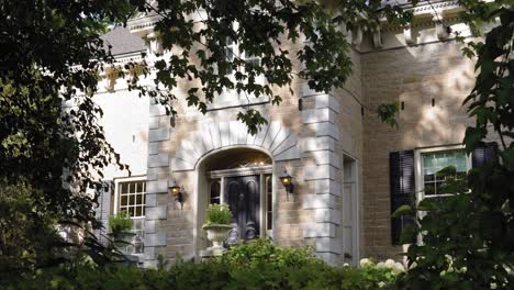 elegant front of a stone mansion from the treed garden in the front yard at the strathmere wedding and event center in ottawa, canada