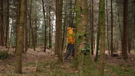 joven europeo con chaqueta amarilla brillante camina en el bosque, muñeca de lado