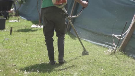 gardener cutting grass of garden corners with weed cutter